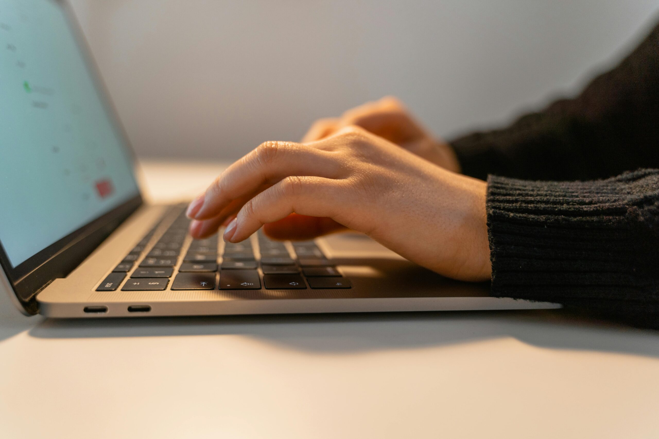 Close-up view of hands typing on a laptop keyboard, illustrating the concept of remote work and technology.
